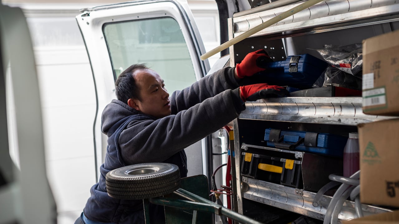 Photo of an HVAC contractor reaching for tools in the back of a service van