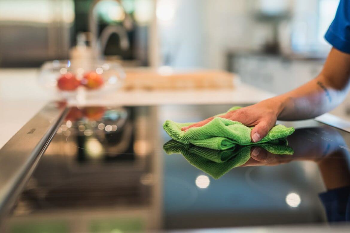 woman cleaning stovetop with cloth