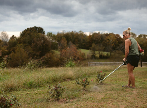 Kristy Boase of MIL-SPEC Landscaping trimming grass on a cloudy day