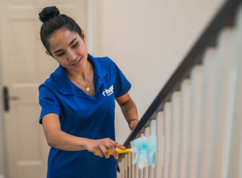 woman feather dusting banister